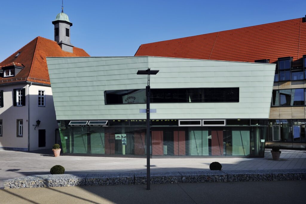 Das Verwaltungsgebäude von Weilheim an der Teck, bestehend aus einem älteren Teil mit einem Kupfertürmchen und einem Neubau mit grüner Außenwand